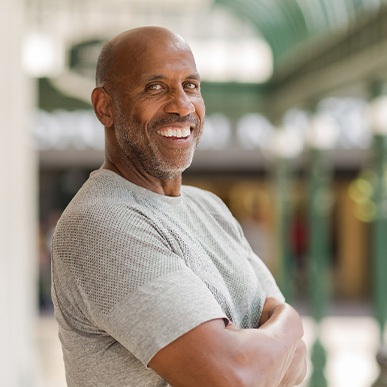 Man in gray shirt smiling outside