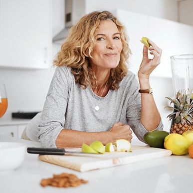 Woman smiling while enjoying snack in kitchen
