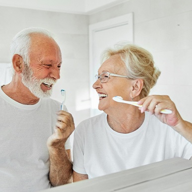 Senior couple smiling while brushing their teeth
