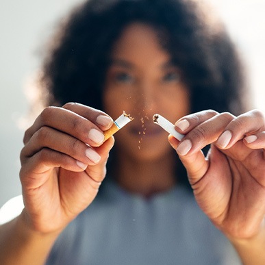 Closeup of woman breaking cigarette