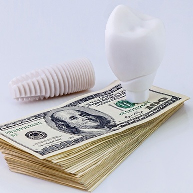 A dental implant on a stack of money