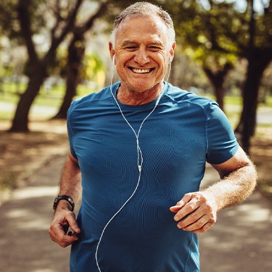 Senior man smiling while jogging outside