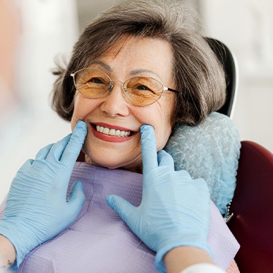 Dentist with blue gloves looking at senior woman's smile